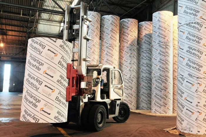 Forklift handling large paper rolls in a warehouse